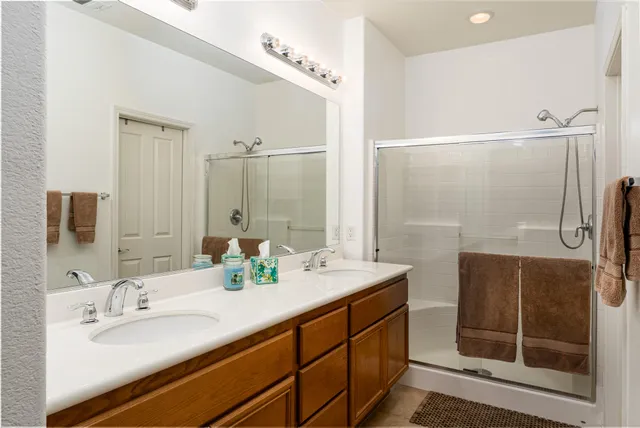 a bathroom with a double vanity sink mirror and shower