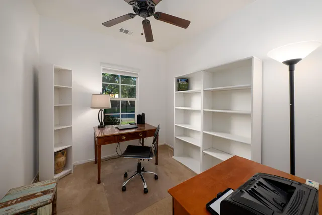 a view of a workspace with furniture and a window