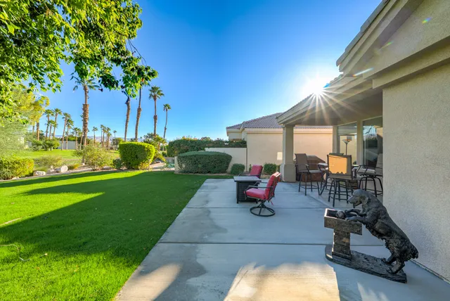 a view of a backyard with table and chairs potted plants and a palm tree
