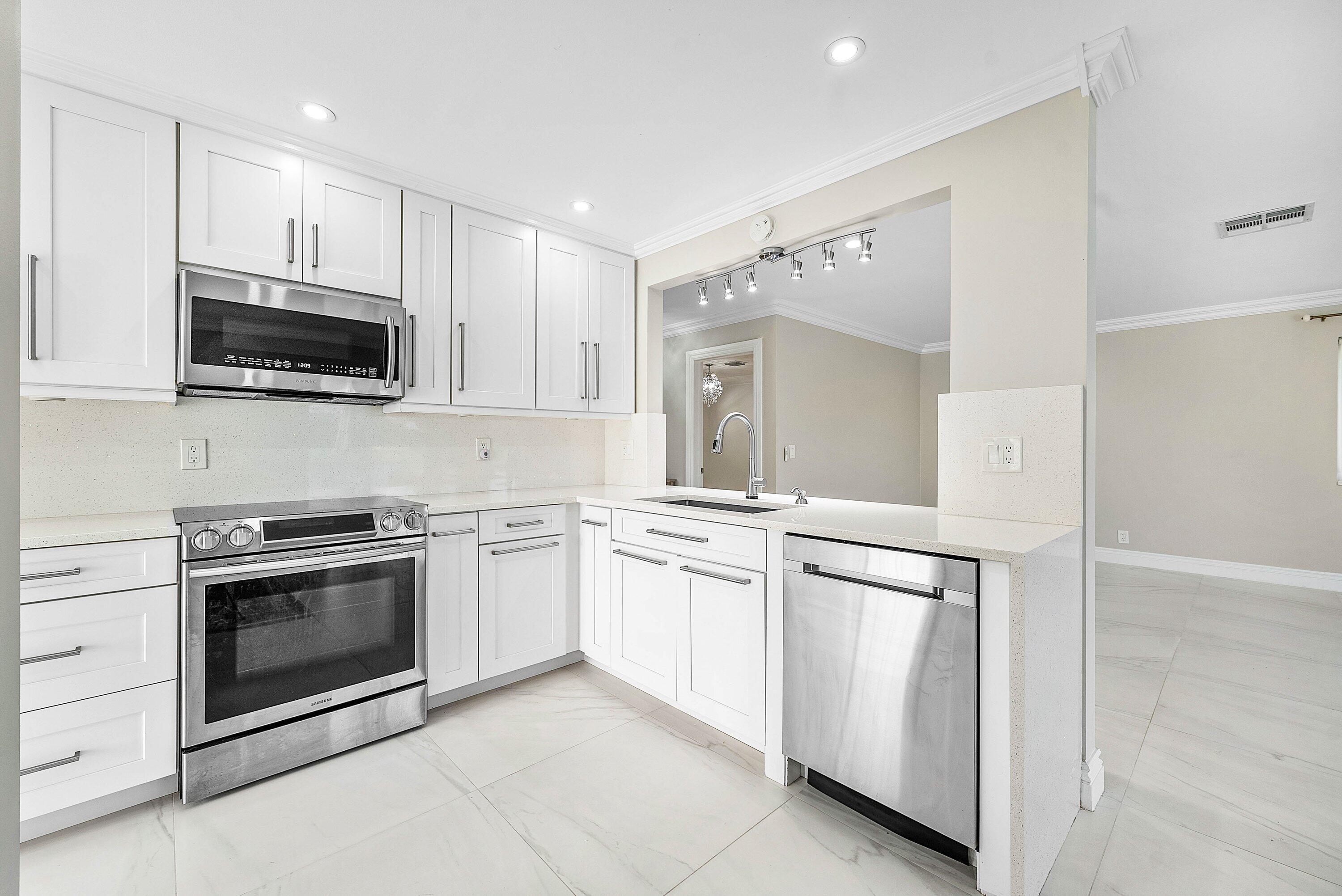 322 Cedar Key Circle Atlantis, FL 33462 - Photo 13 of 55 a kitchen with white cabinets and stainless steel appliances