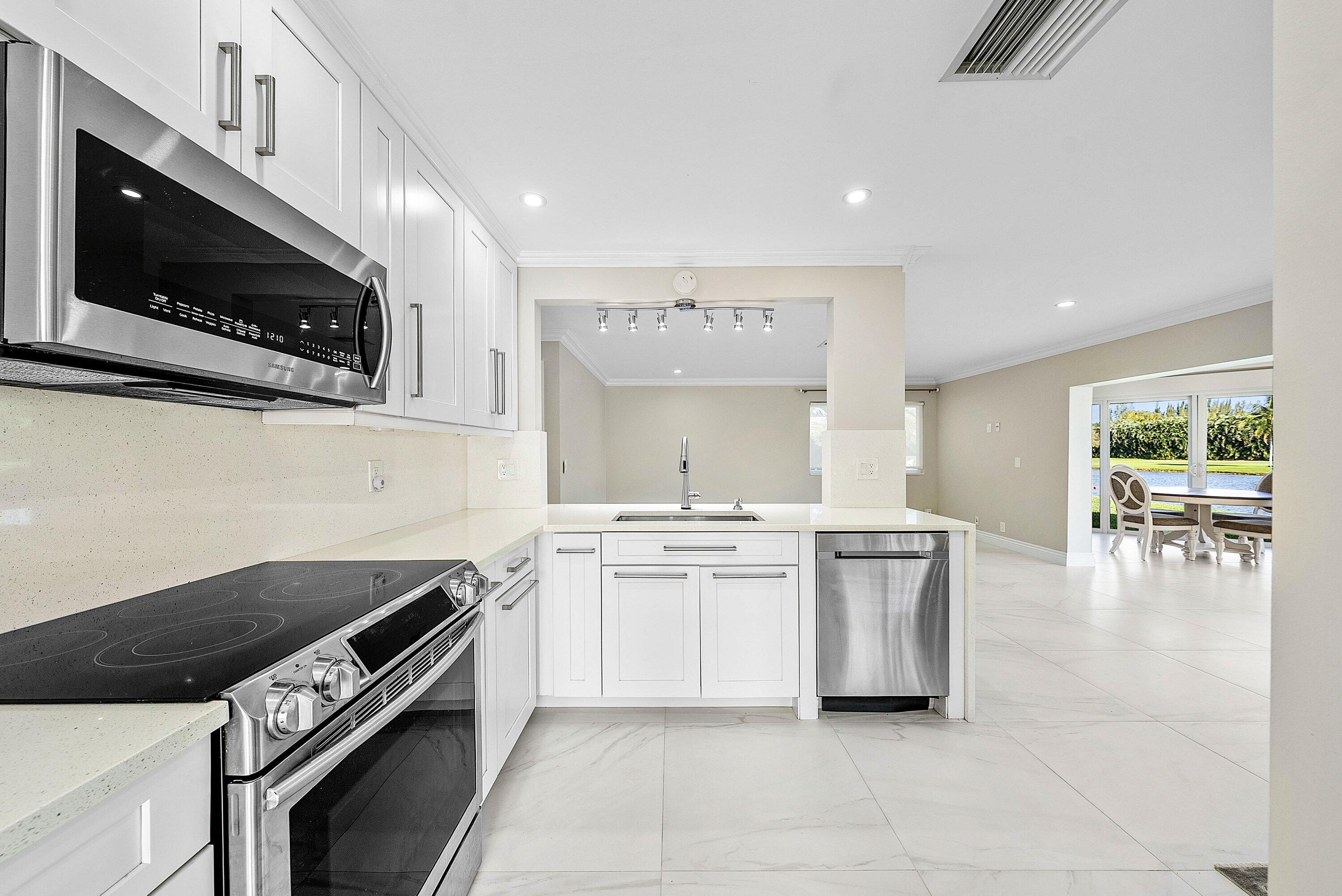 322 Cedar Key Circle Atlantis, FL 33462 - Photo 15 of 55 a kitchen with stainless steel appliances a stove a sink and a microwave