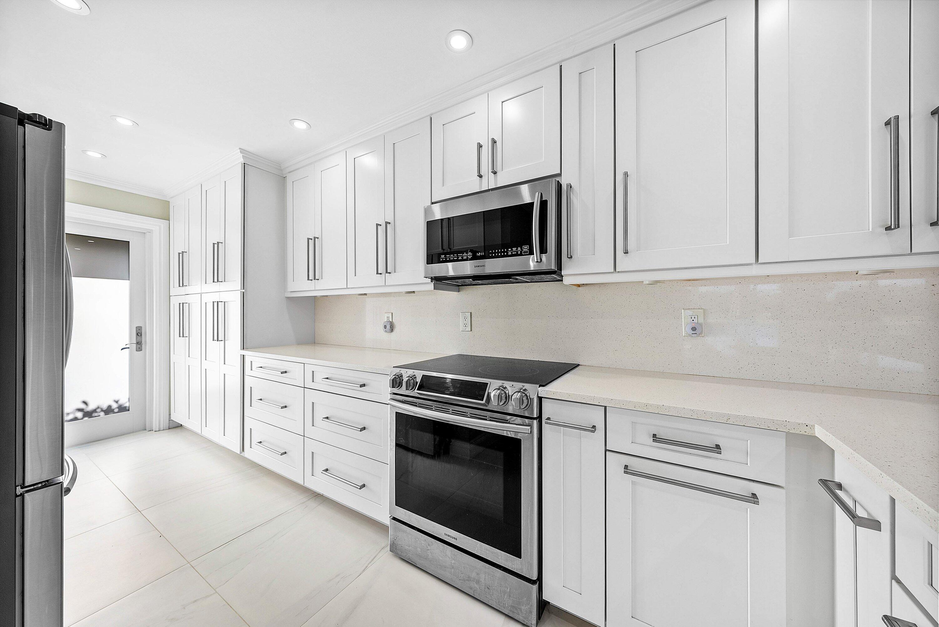 322 Cedar Key Circle Atlantis, FL 33462 - Photo 17 of 55 a kitchen with granite countertop white cabinets stainless steel appliances and sink