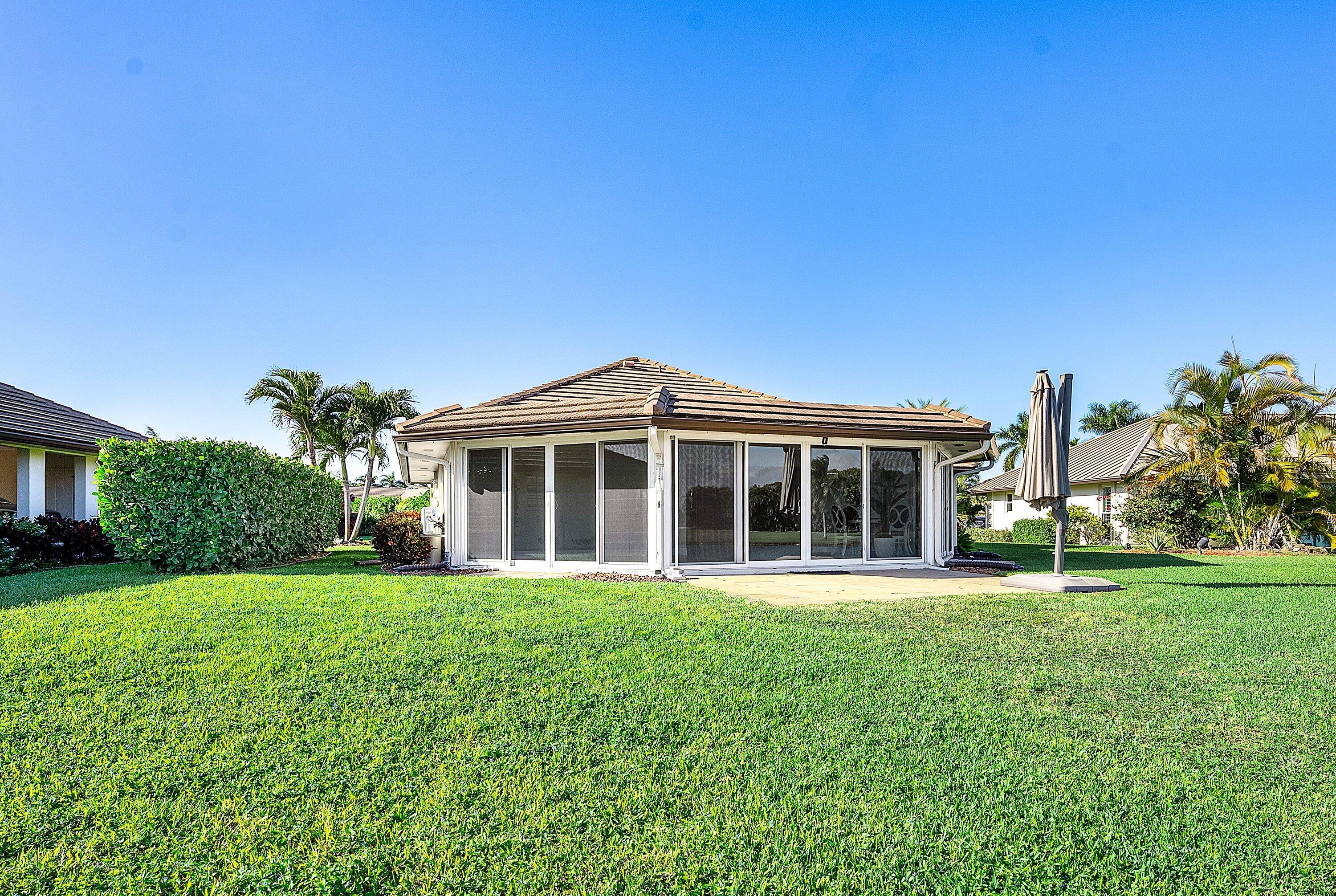 322 Cedar Key Circle Atlantis, FL 33462 - Photo 34 of 55 a front view of a house with a garden and trees
