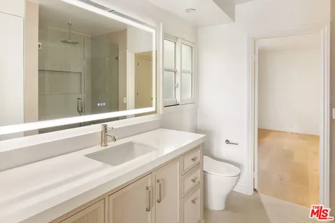 a bathroom with a sink a toilet a large mirror and shower