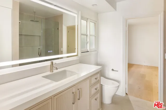 a bathroom with a sink a toilet a large mirror and shower