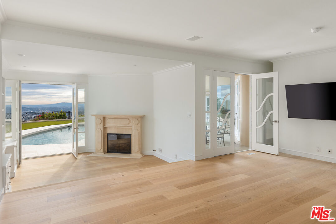 1630 Carla Ridge Beverly Hills, CA 90210 - Photo 9 of 22 an empty room with fireplace and fan