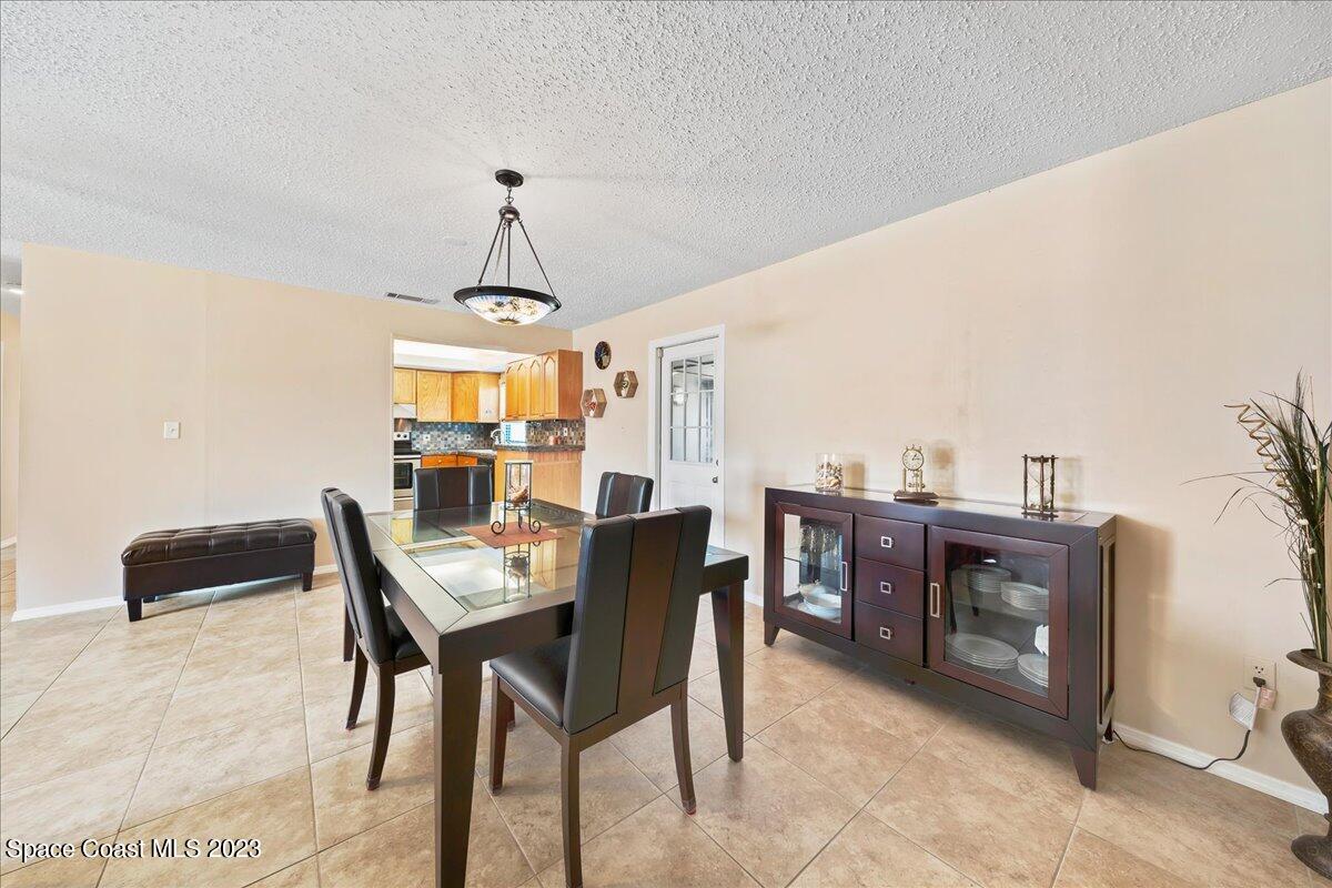 1379 Cromey Road Northeast Palm Bay, FL 32905 - Photo 7 of 25 a dining room with a wooden table and chairs