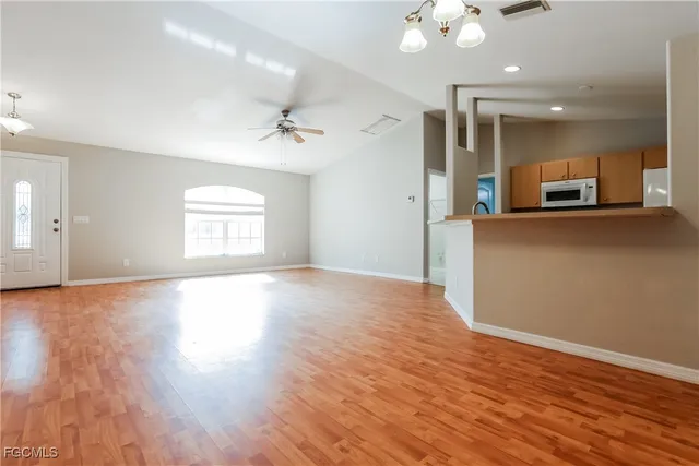 a view of a room with kitchen appliances and wooden floor