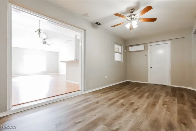 an empty room with a chandelier fan and windows