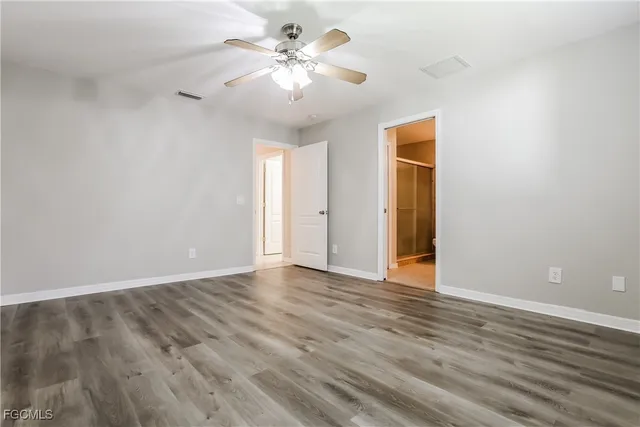 a view of an empty room with chandelier fan and wooden floor