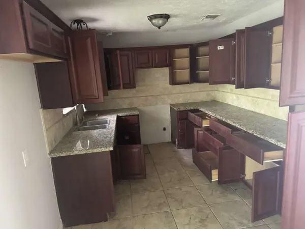 a kitchen with granite countertop a sink a stove and a refrigerator