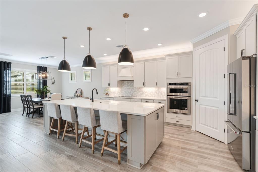 13303 Rinella Street Venice, FL 34293 - Photo 13 of 52 a kitchen with stainless steel appliances kitchen island granite countertop a table chairs sink and cabinets
