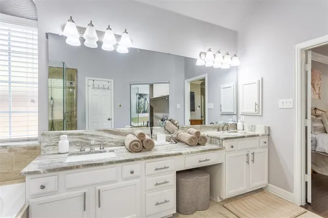 a bathroom with double vanity sinks a vanity a lamp and a mirror