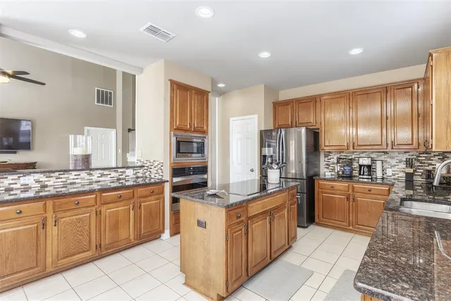 a kitchen with stainless steel appliances granite countertop a stove top oven a refrigerator a sink and dishwasher