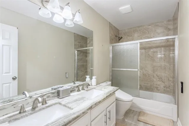 a bathroom with a granite countertop sink a toilet and shower