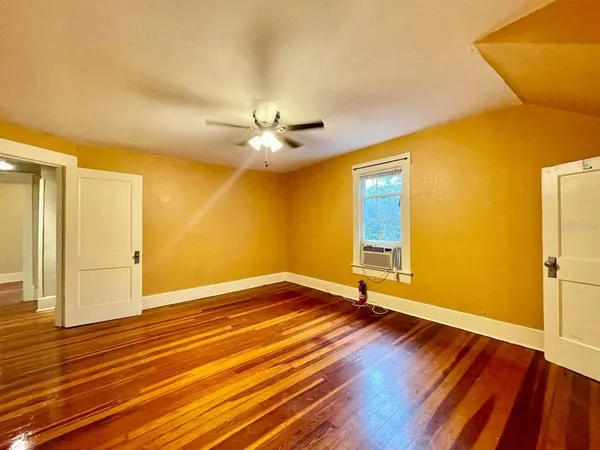 a view of an empty room with wooden floor and a window