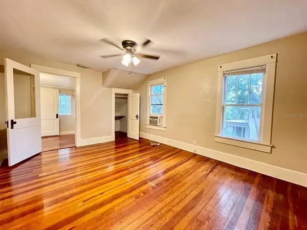 a view of an empty room with wooden floor and a window