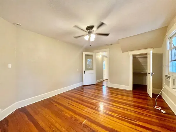 a view of an empty room with window and wooden floor