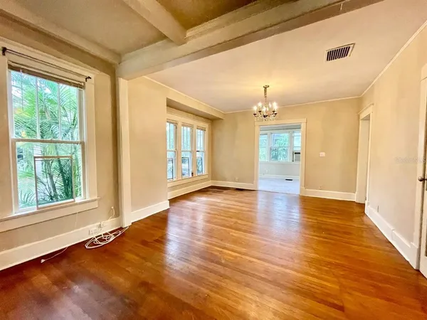 a view of an empty room with window and wooden floor
