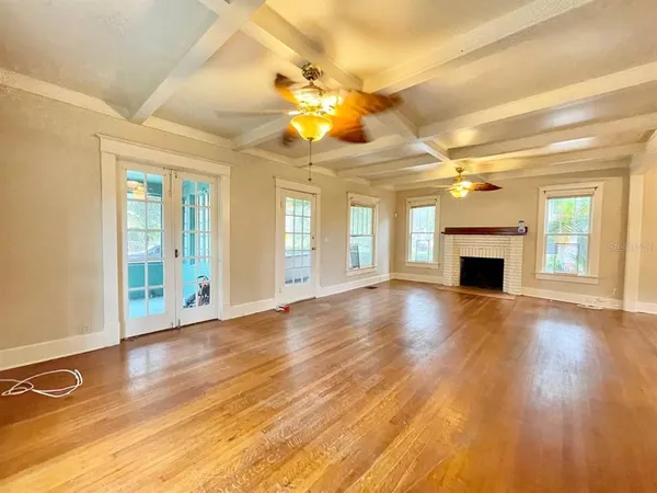 a view of an empty room with window and wooden floor