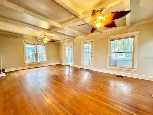 an empty room with wooden floor and windows