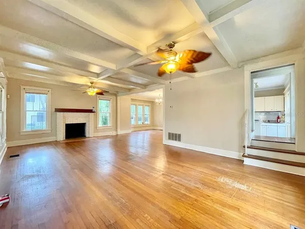 a view of an empty room with a fireplace and wooden floor