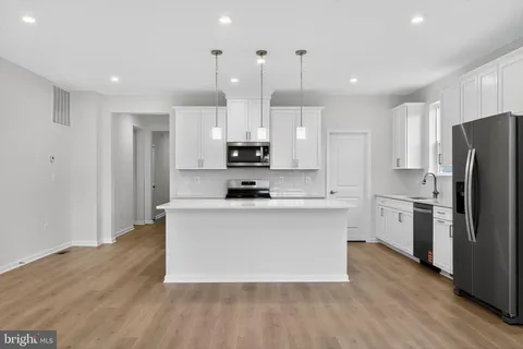 a kitchen with stainless steel appliances a refrigerator a stove a sink and white cabinets