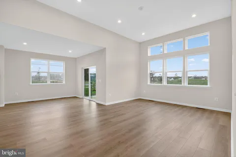 a view of an empty room with wooden floor and windows