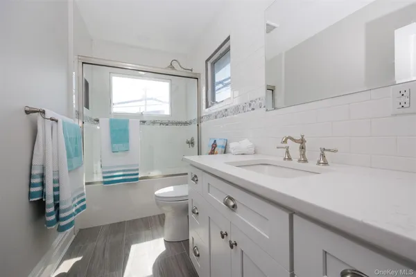 a bathroom with a granite countertop sink a toilet and a shower