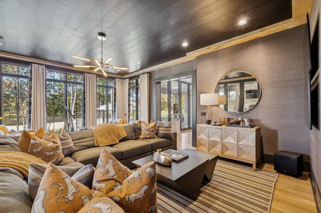 a living room with a couch a fireplace a large window and a flat tv screen