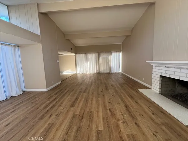 a view of empty room with wooden floor and fireplace