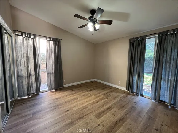 an empty room with wooden floor and windows