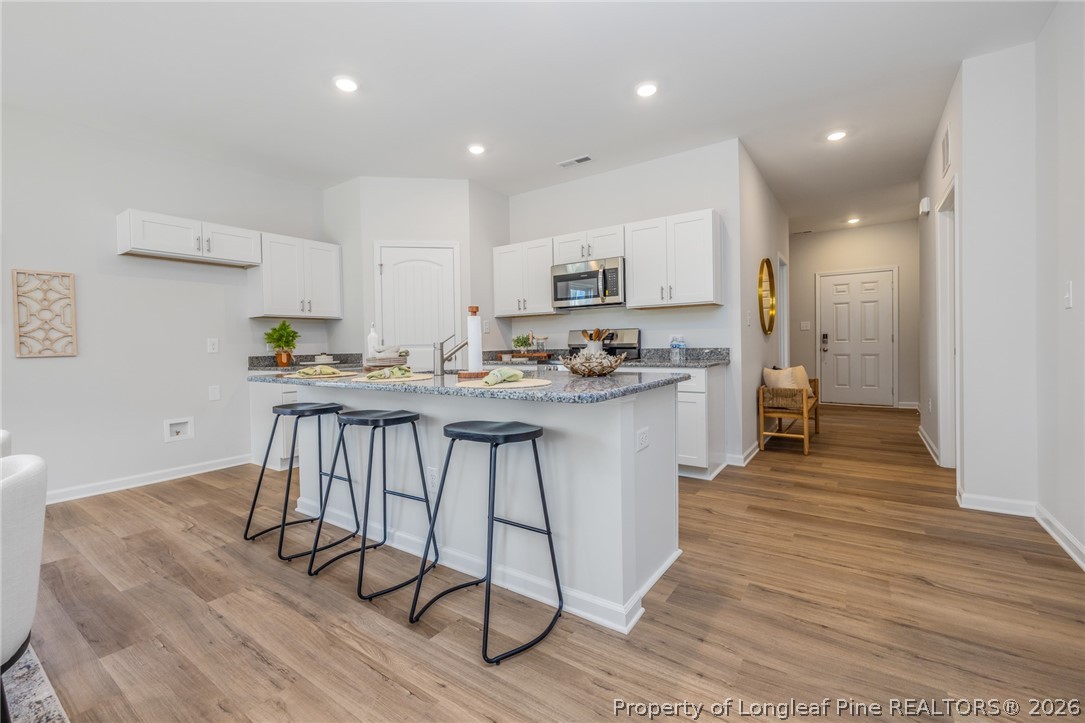 5421 Short Leaf (lot 109) Road Raeford, NC 28376 - Photo 15 of 29 a kitchen with stainless steel appliances kitchen island granite countertop a refrigerator a stove a sink and white cabinets with wooden floor