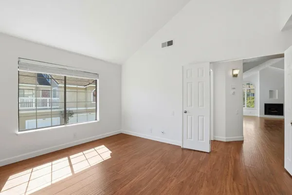 a view of empty room with wooden floor and fan