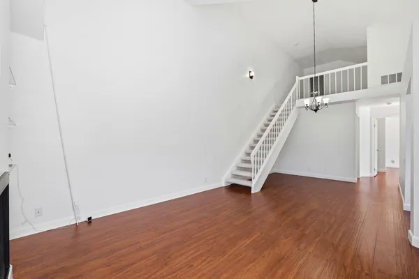 a view of an empty room with wooden floor and stairs