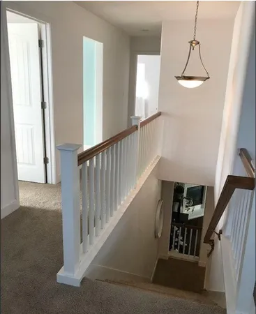 a view of staircase with railing and white walls