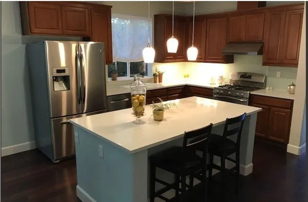 a kitchen with stainless steel appliances a dining table chairs and refrigerator