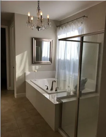 a bathroom with a granite countertop sink a large mirror a bathtub and shower
