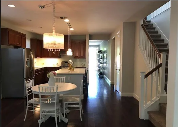 a kitchen with stainless steel appliances kitchen island granite countertop a refrigerator a stove a microwave oven a dining table and chairs with wooden floor