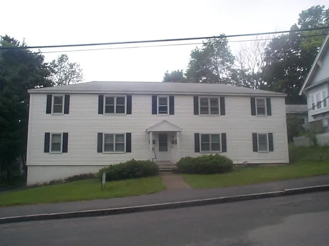 a front view of a house with a garden and trees
