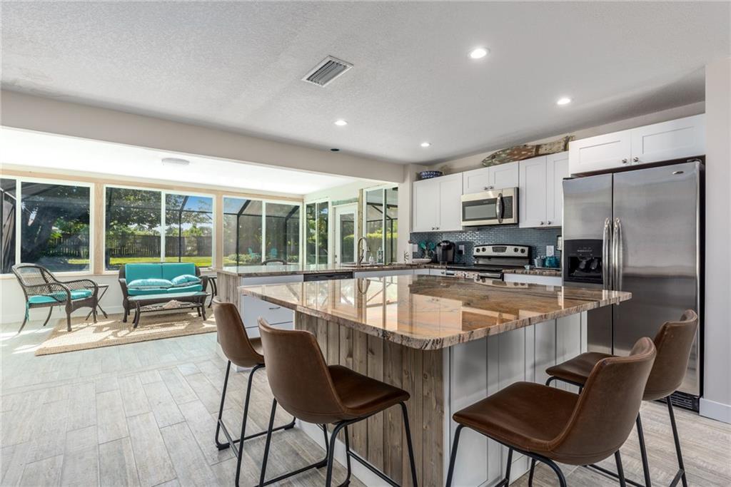 1453 Northwest Spruce Ridge Drive Stuart, FL 34994 - Photo 13 of 27 a dining hall with stainless steel appliances granite countertop a stove a refrigerator a kitchen island a table and chairs