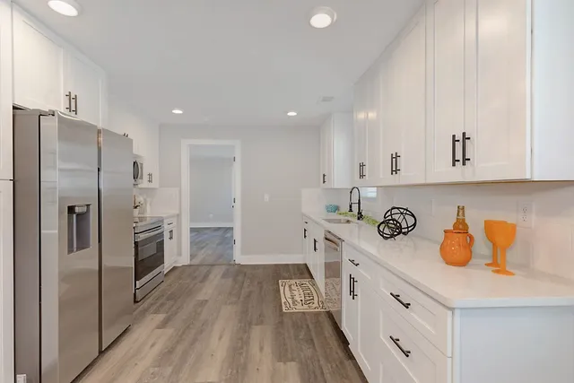 a kitchen with white cabinets and sink