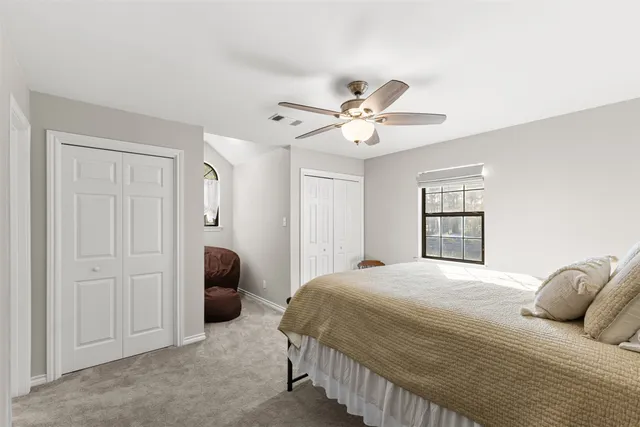 a bedroom with a bed ceiling fan and a window
