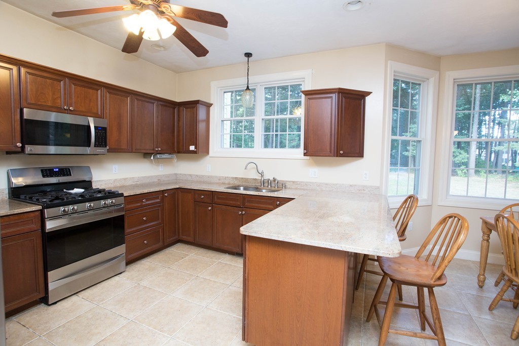 24 Zina Road Hudson, MA 01749 - Photo 2 of 25 a kitchen with stainless steel appliances granite countertop a stove top oven a sink dishwasher a dining table and chairs with wooden floor