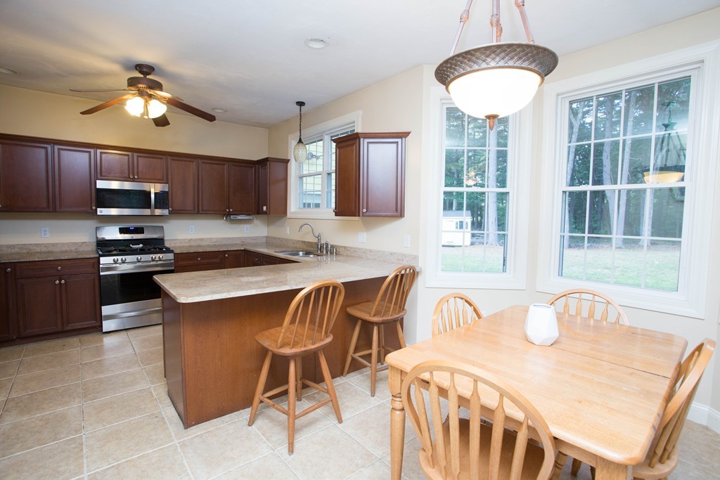 24 Zina Road Hudson, MA 01749 - Photo 3 of 25 a kitchen with stainless steel appliances granite countertop a stove top oven a sink a dining table and chairs with wooden floor