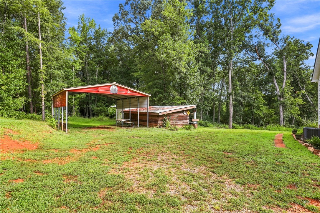 525 Shirley Store Road Anderson, SC 29621 - Photo 23 of 46 Mature trees frame a spacious grassy clearing complete with outdoor storage structures.