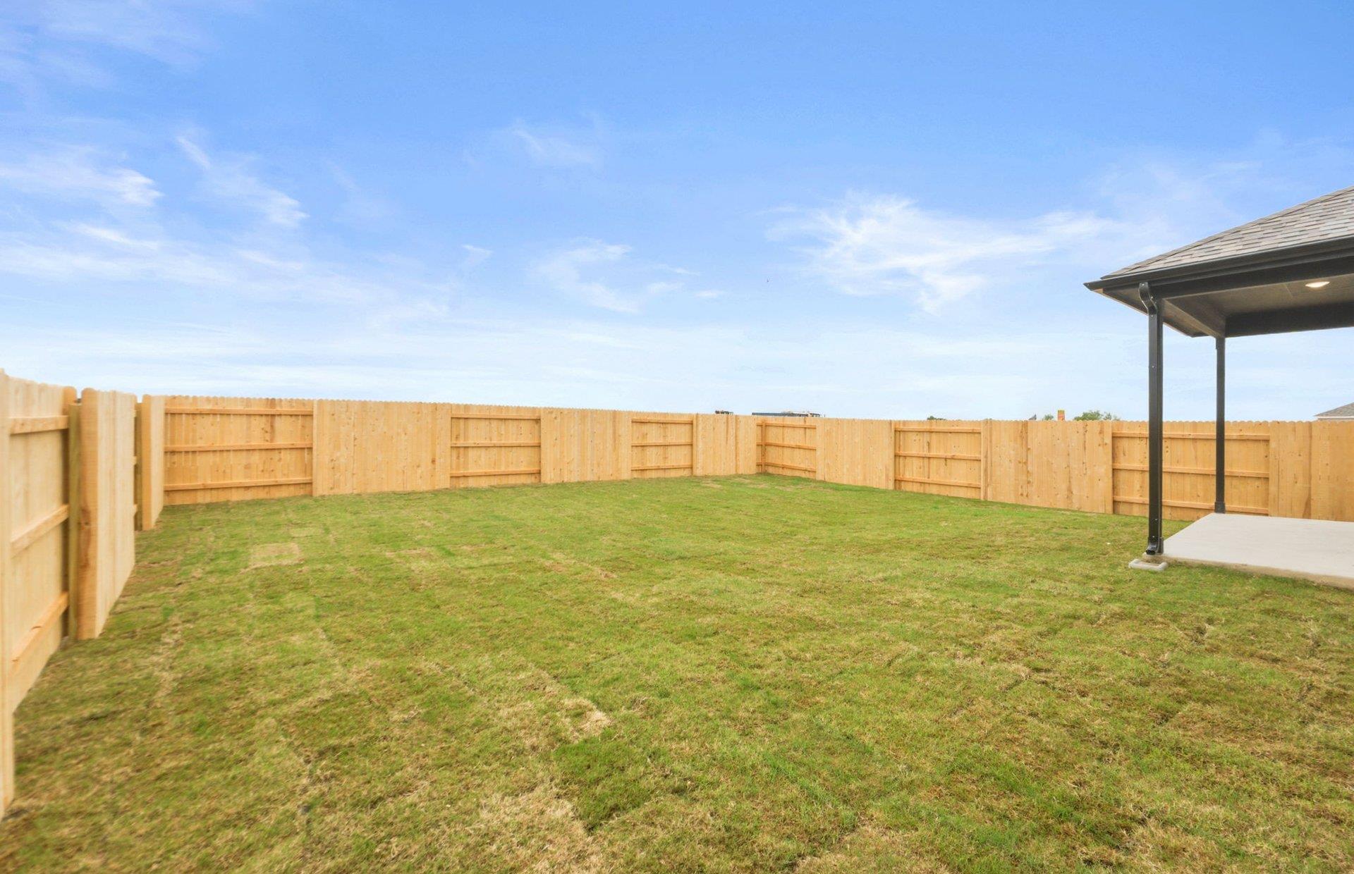 545 Henry Milton Road Georgetown, TX 78626 - Photo 19 of 33 An expansive green lawn is fully enclosed by a sturdy wooden privacy fence.