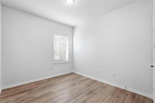 an empty room with wooden floor and window