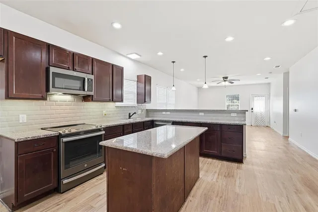 a kitchen with stainless steel appliances granite countertop wooden cabinets a sink and dishwasher a oven with wooden floors