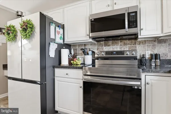 a kitchen with stainless steel appliances white cabinets and a stove top oven